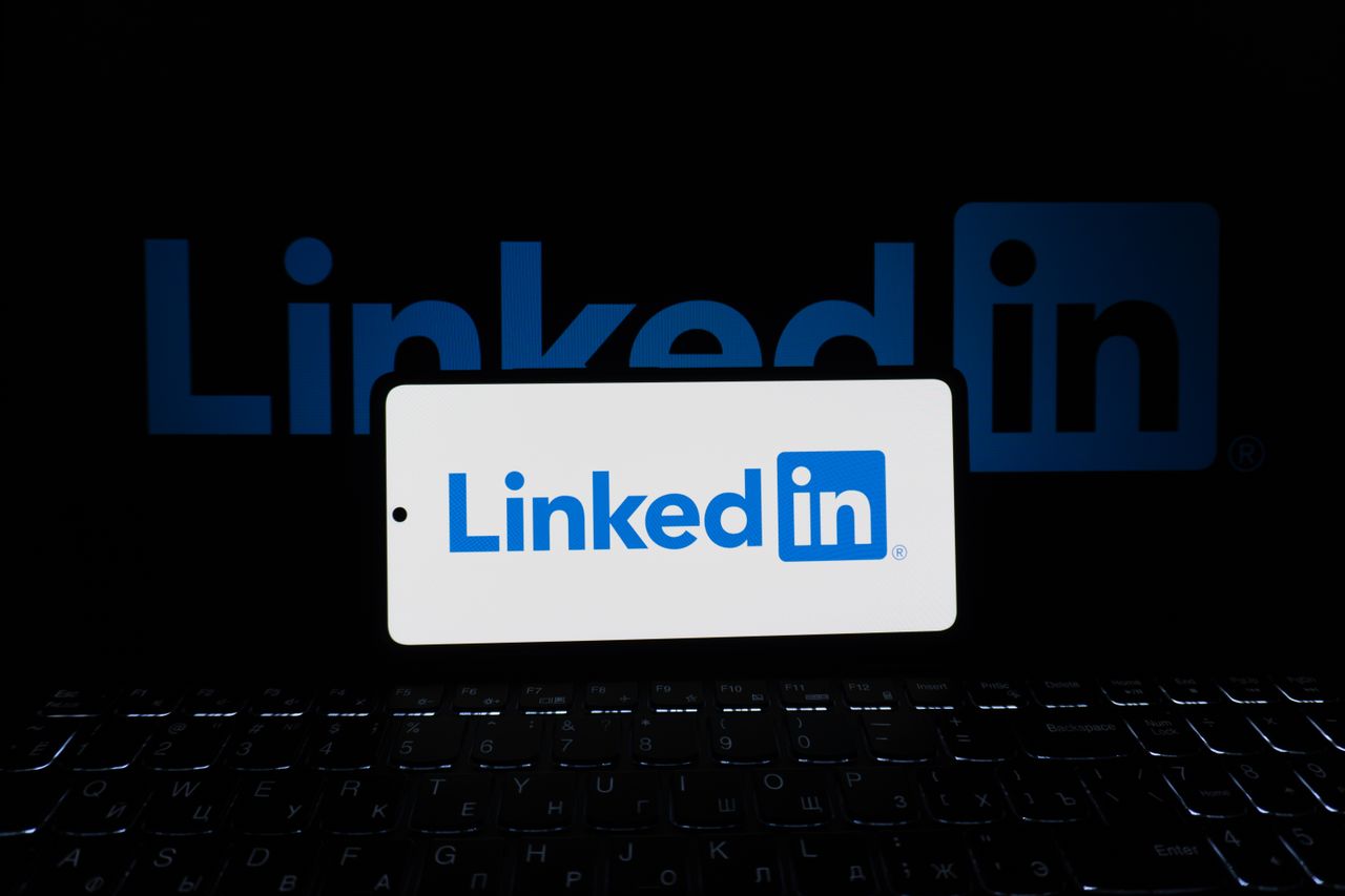 services-04 Smartphone showing LinkedIn logo with keyboard and large background logo, business theme.